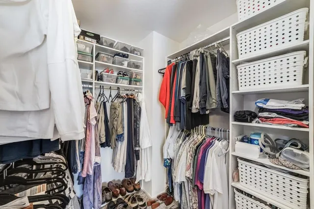 a view of walk in closet with clothes and shoes
