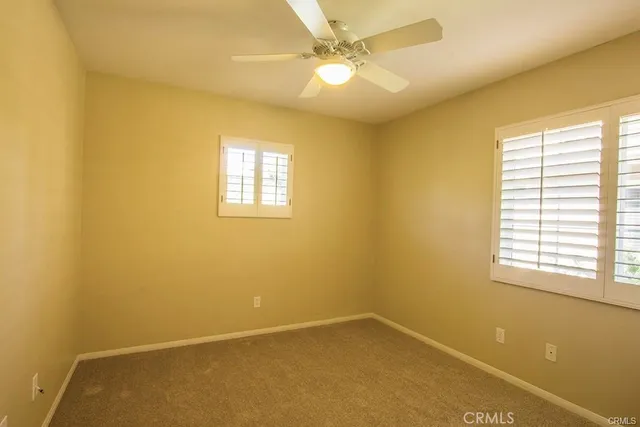 an empty room with a window and a ceiling fan
