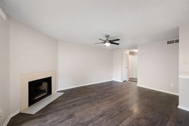 a view of an empty room with wooden floor fireplace and a window