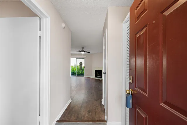 a view of a hallway with wooden floor and a room