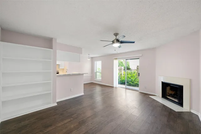 a view of an empty room with a fireplace and wooden floor