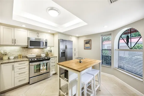 a kitchen with stainless steel appliances kitchen island granite countertop a stove refrigerator and cabinets