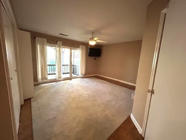 an empty room with chandelier fan and windows