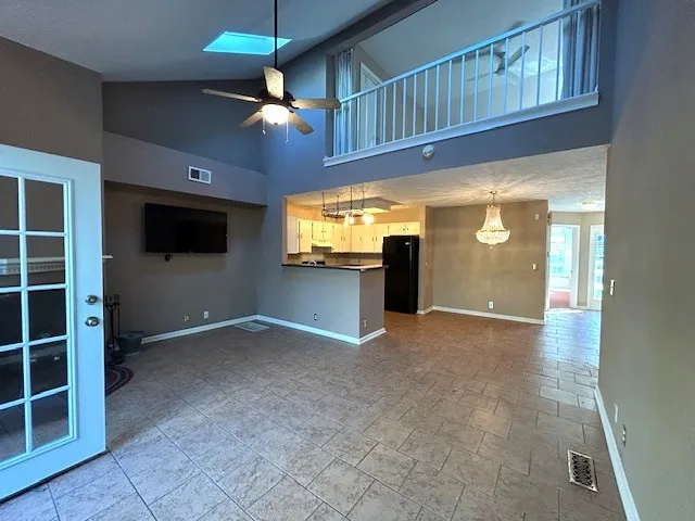 a view of an empty room with a window and kitchen view