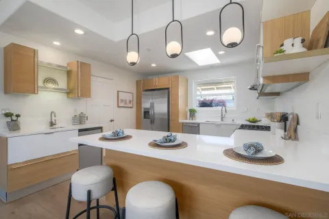 a kitchen with stainless steel appliances kitchen island granite countertop a table chairs and a sink