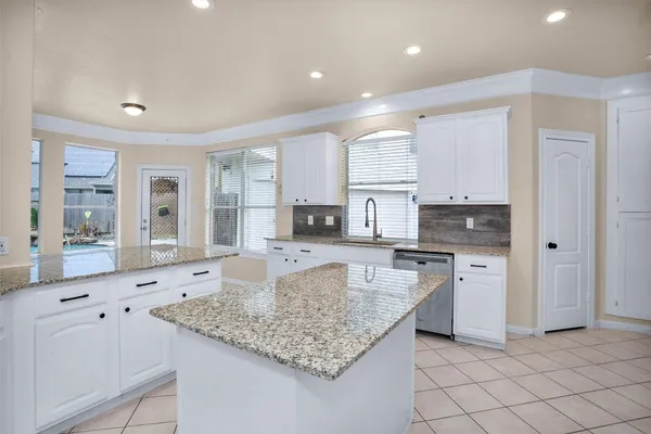 a large kitchen with granite countertop white cabinets and a window