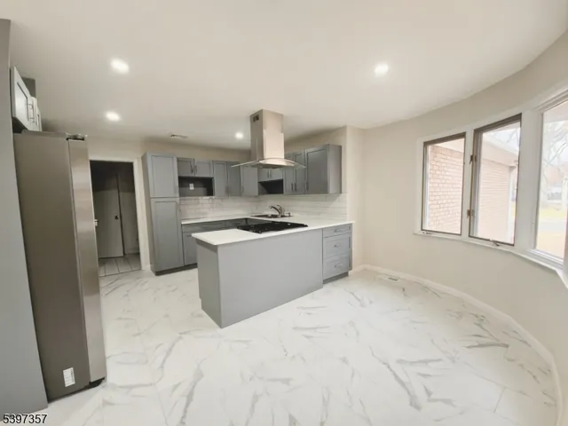 a kitchen with stainless steel appliances kitchen island a refrigerator sink and cabinets