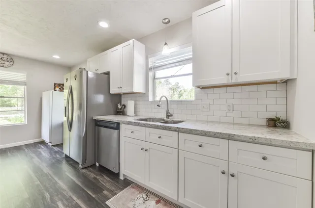 a kitchen with a sink dishwasher a refrigerator and cabinets