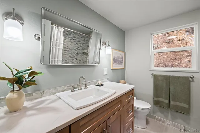 a bathroom with a granite countertop sink mirror vanity and toilet