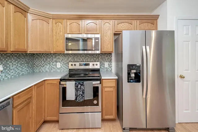 a kitchen with stainless steel appliances granite countertop a refrigerator a stove and a sink