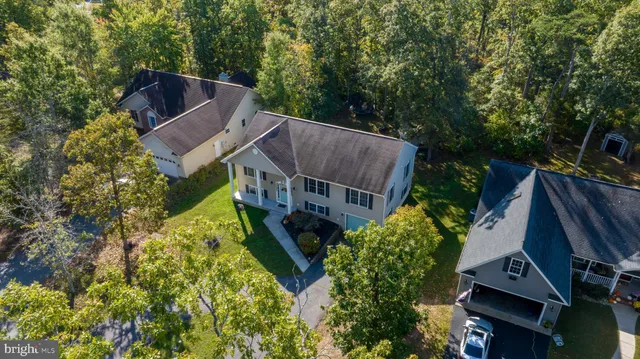 an aerial view of a house with garden space and trees all around