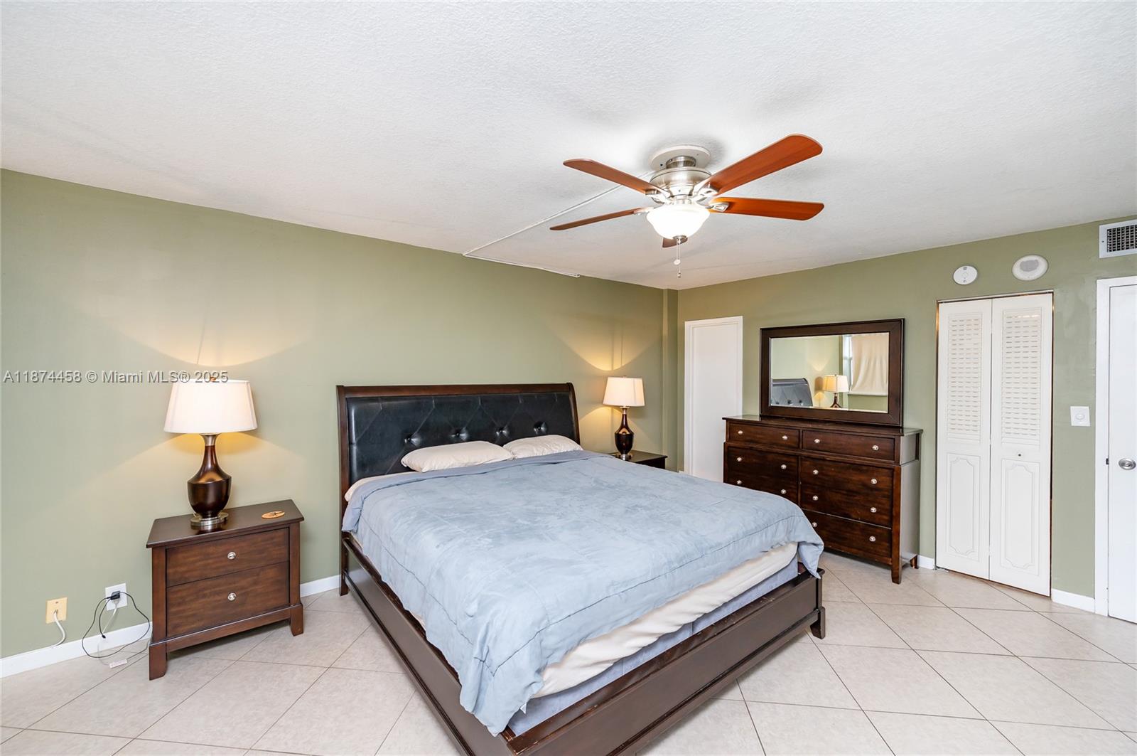 100 Golden Isles Drive, Unit 104 Hallandale Beach, FL 33009 - Photo 21 of 28 a bedroom with a bed and a lamp on dresser