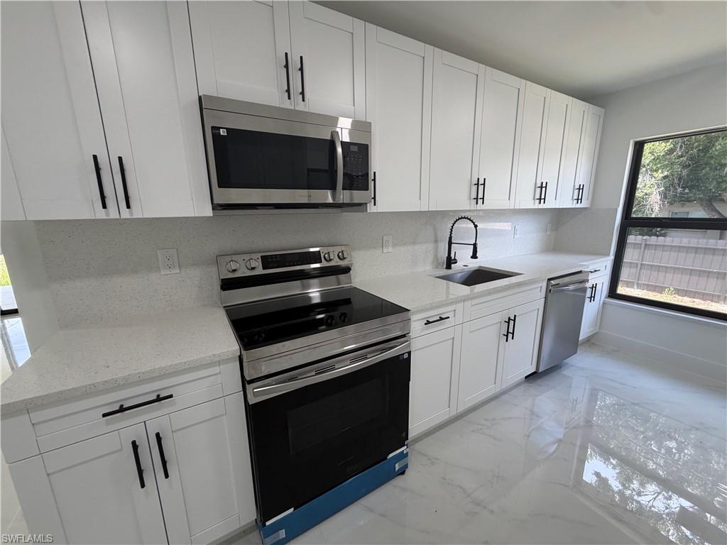 15 Louisiana Road Lehigh Acres, FL 33936 - Photo 14 of 22 a kitchen with stainless steel appliances white cabinets and a stove top oven
