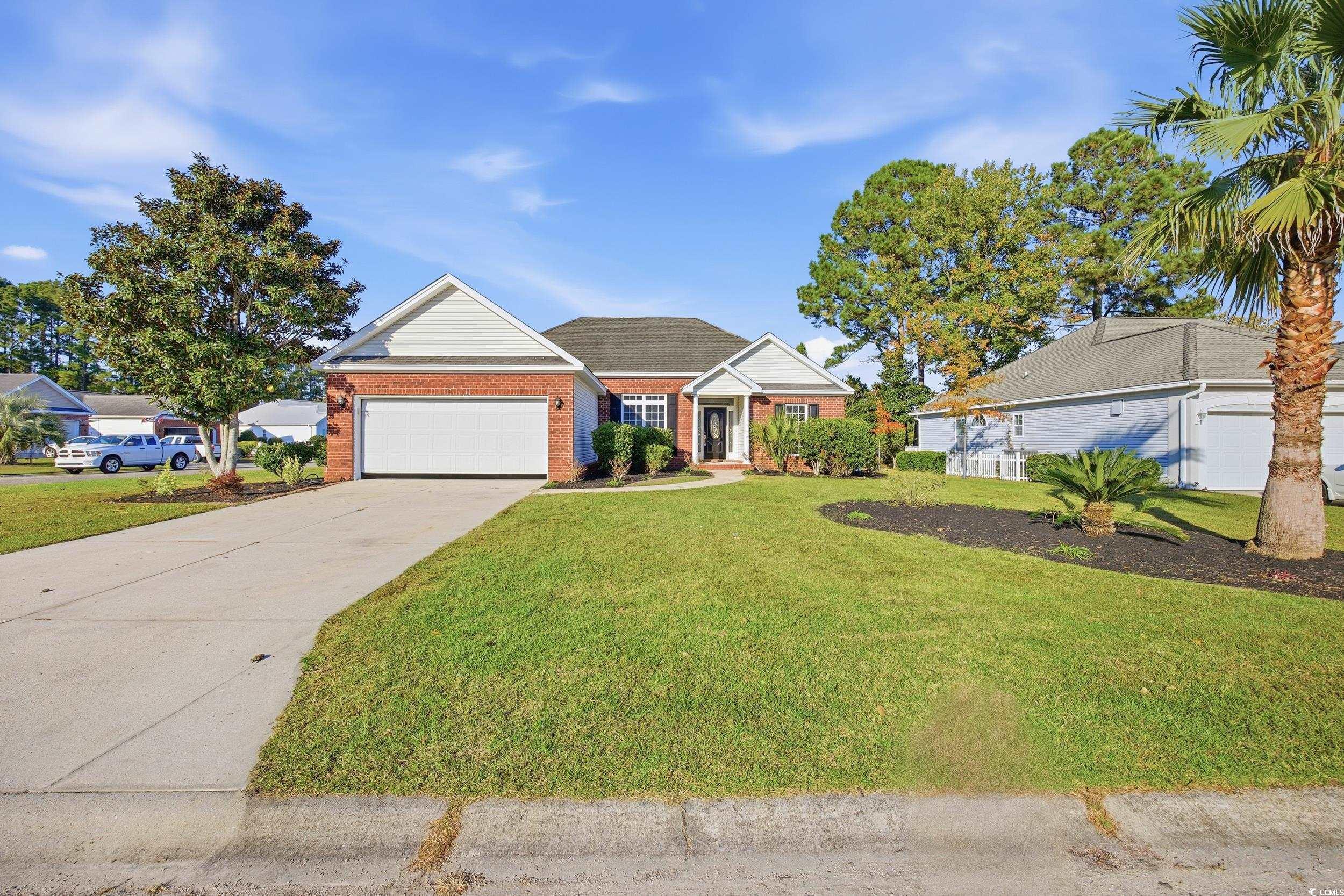 View of front of property with a front lawn, concrete driveway, brick siding, and an attached garage