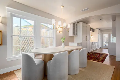 a view of a dining room and livingroom with furniture wooden floor a chandelier