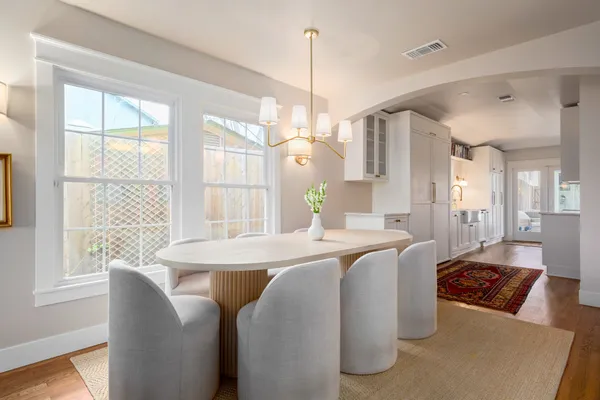 a view of a dining room and livingroom with furniture wooden floor a chandelier