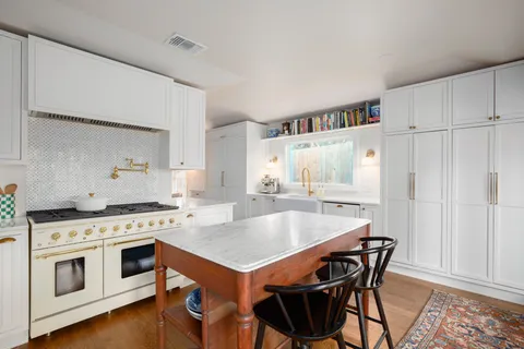 a open kitchen with stainless steel appliances granite countertop a stove top oven a refrigerator a sink dishwasher and white cabinets with wooden floor