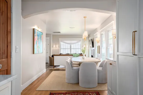 a dining room with kitchen island stainless steel appliances furniture a large window and a refrigerator