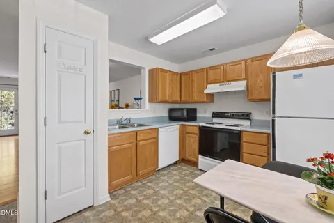 a kitchen with a refrigerator a stove a sink dishwasher and white cabinets with wooden floor