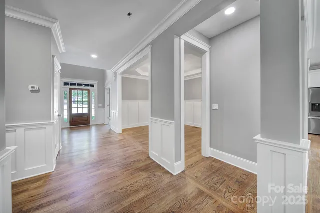 a large kitchen with stainless steel appliances granite countertop a stove a sink dishwasher a refrigerator and white cabinets with wooden floor