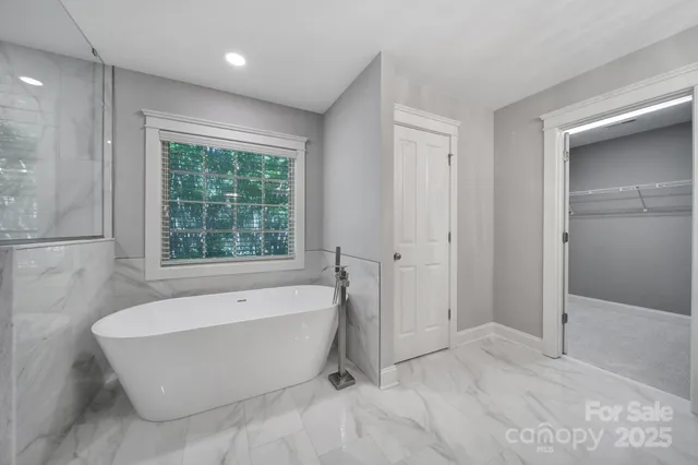 a bathroom with a large tub a shower and view