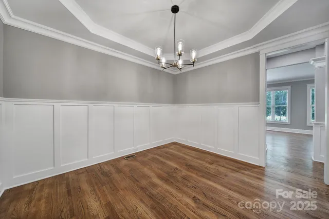 a view of a hallway with wooden floor and chandelier