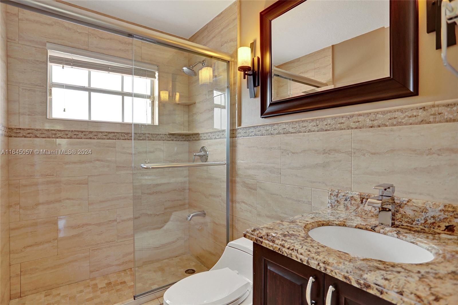15591 Southwest 42nd Lane Miami, FL 33185 - Photo 31 of 60 a bathroom with a granite countertop sink toilet a mirror and shower