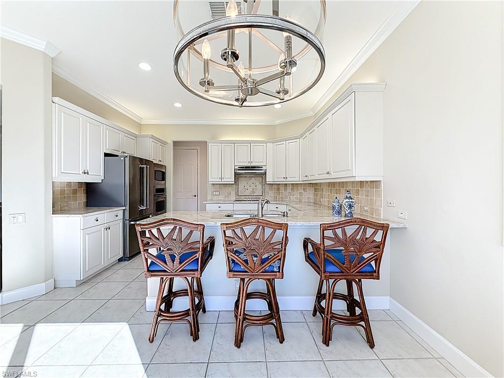 3051 Lancaster Drive, Unit 2 Naples, FL 34105 - Photo 20 of 43 a view of dining room and kitchen with chandelier