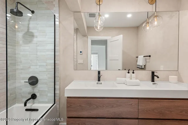 a bathroom with a sink a light fixture and a glass door shower