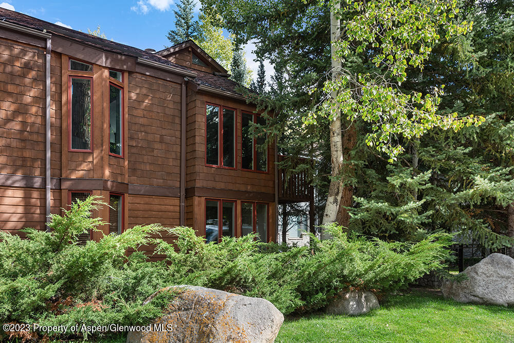 900 East Durant Avenue, Unit 116 Aspen, CO 81611 - Photo 2 of 19 a view of a brick house with a large windows and a yard with plants and large trees