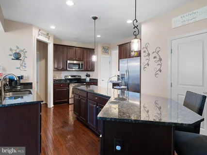 a kitchen with kitchen island granite countertop stainless steel appliances cabinets a sink and a center island