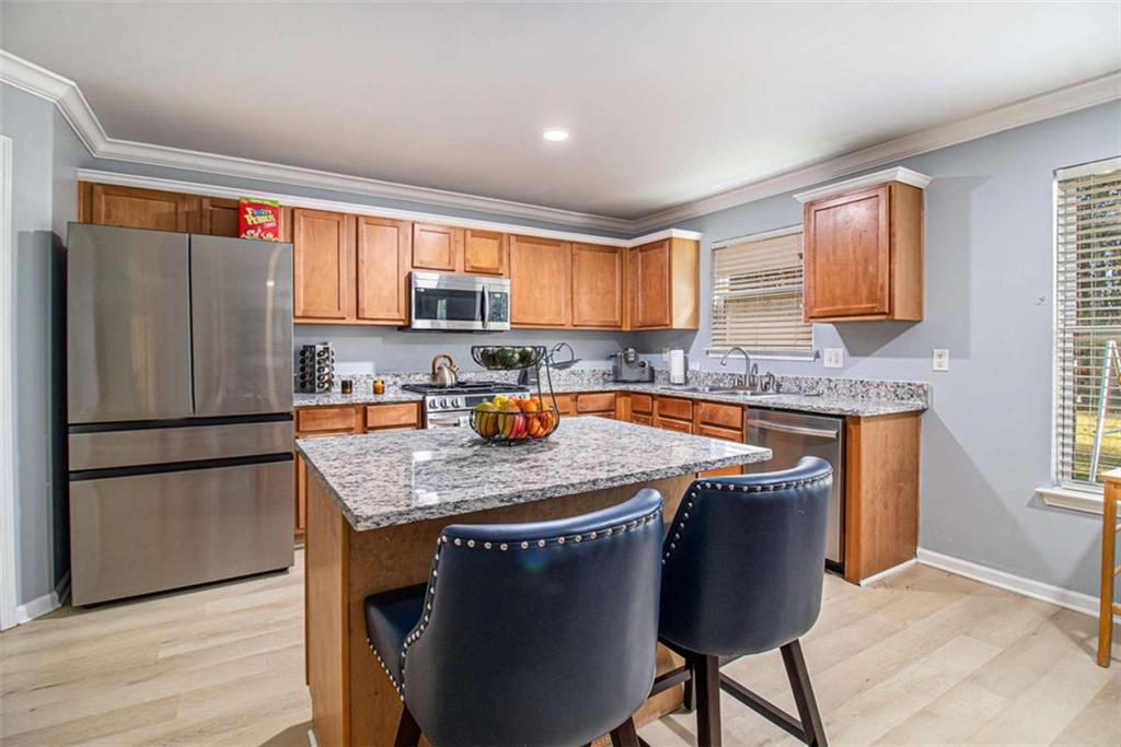 550 Windsor Way Fairburn, GA 30213 - Photo 10 of 28 a kitchen with stainless steel appliances granite countertop a refrigerator a sink a stove a dining table and chairs with wooden floor