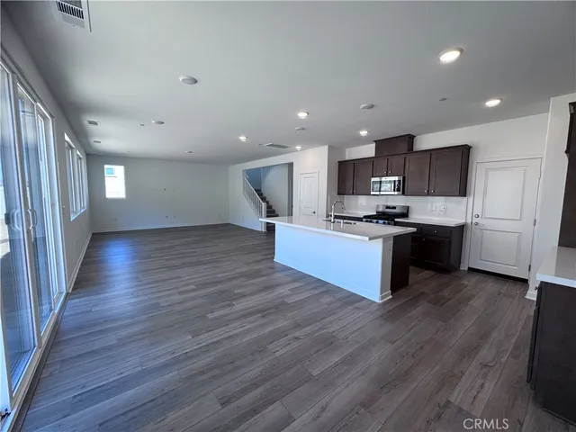 a kitchen with stainless steel appliances kitchen island granite countertop wooden floors and a view of living room