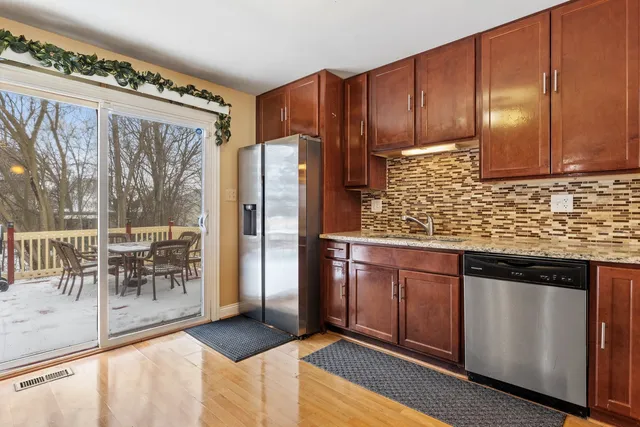 a kitchen with stainless steel appliances granite countertop a refrigerator and a wooden cabinets