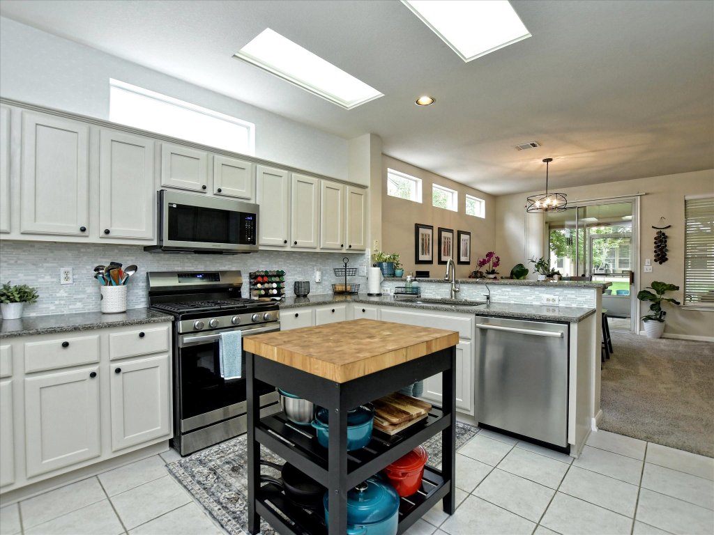 116 Running Water Street Georgetown, TX 78633 - Photo 10 of 25 a kitchen with kitchen island granite countertop a stove top oven a sink a counter top space and cabinets