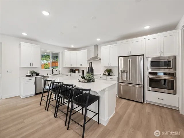 a kitchen with a sink a stove a refrigerator and white cabinets with wooden floor