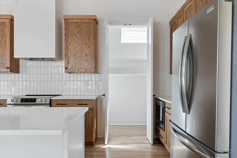a view of a refrigerator in kitchen and an empty room