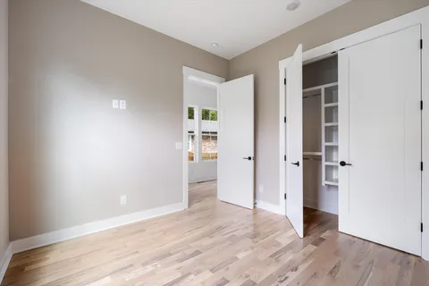 an empty room with wooden floor & closet and windows