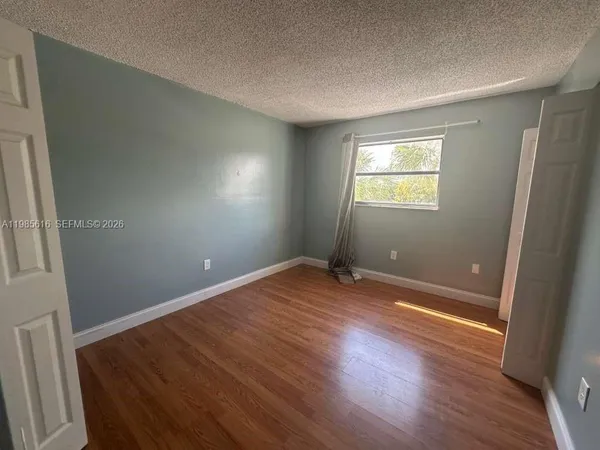 an empty room with wooden floor and a bathroom