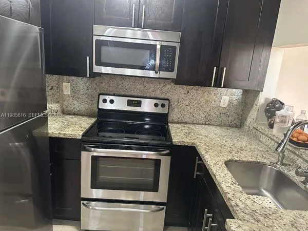 a kitchen with granite countertop cabinets stainless steel appliances and a sink