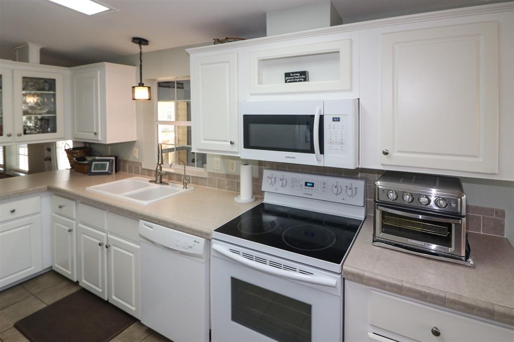 29200 South Jones Loop Road, Unit 522 Punta Gorda, FL 33950 - Photo 21 of 38 a kitchen with white cabinets stainless steel appliances and sink