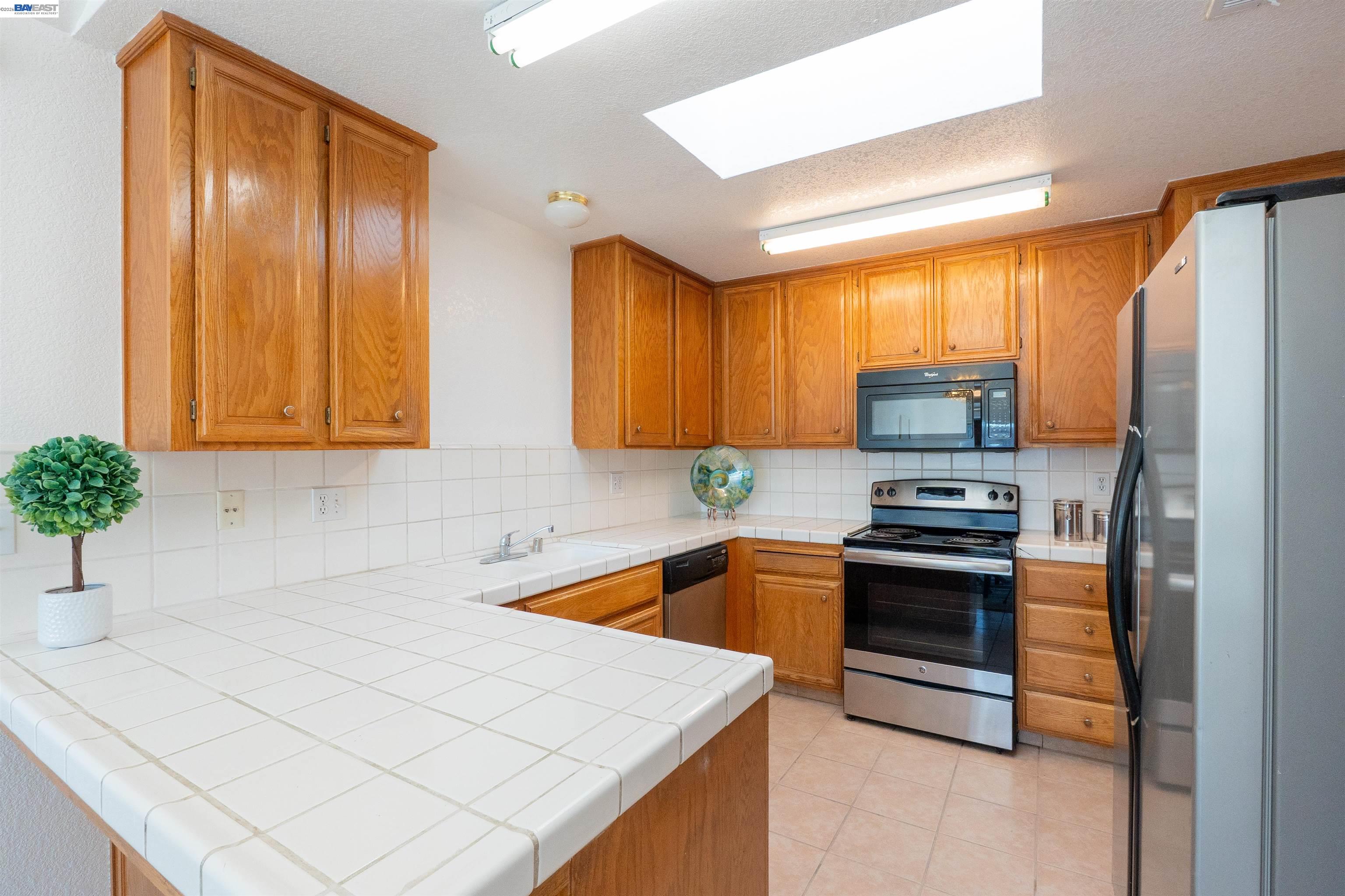 2932 Alcott Court Modesto, CA 95355 - Photo 31 of 39 a kitchen with stainless steel appliances a stove a sink and a microwave