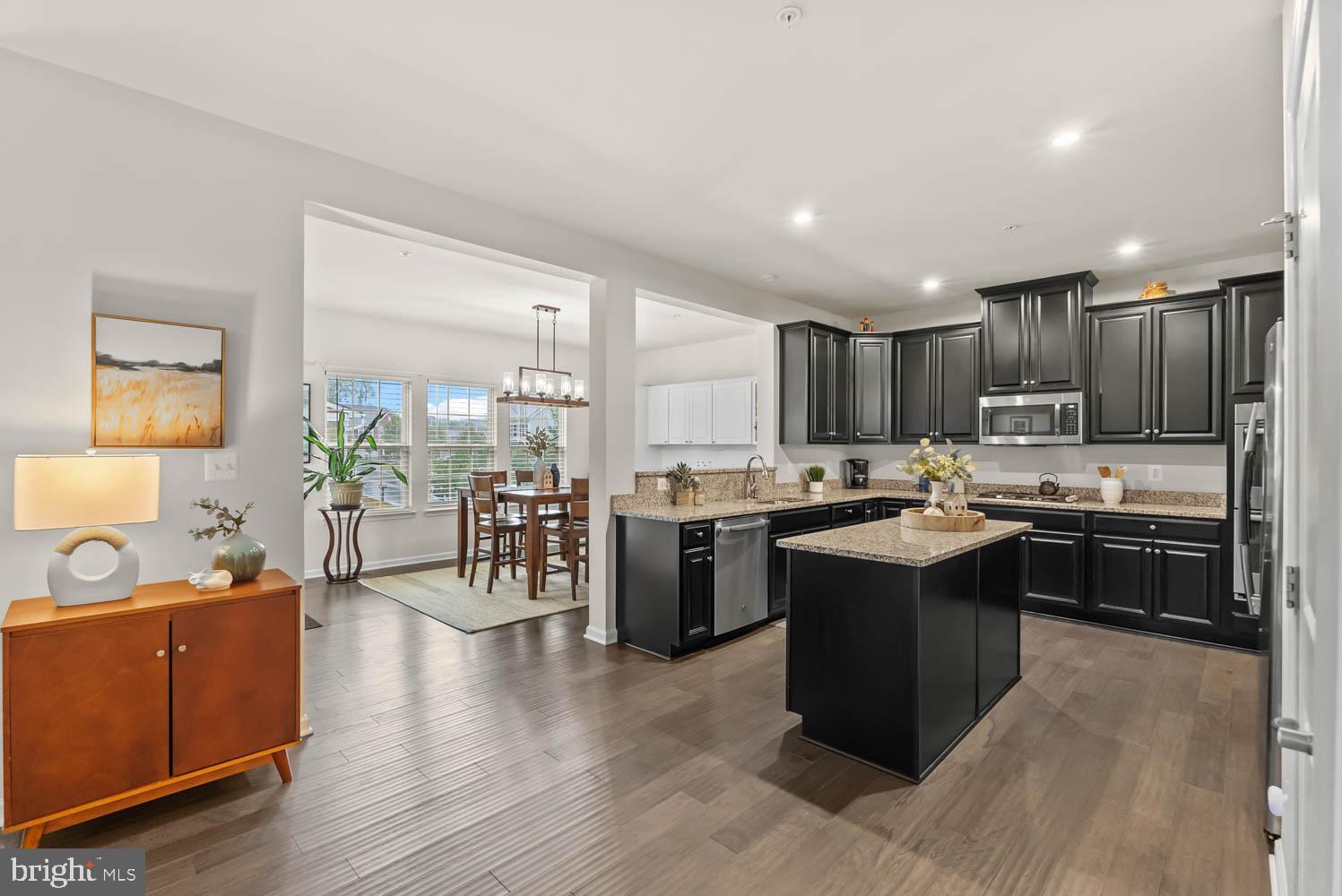 17883 Sugarberry Road Dumfries, VA 22026 - Photo 19 of 53 a kitchen with stainless steel appliances kitchen island granite countertop a refrigerator a sink dishwasher a stove and a dining table with wooden floor
