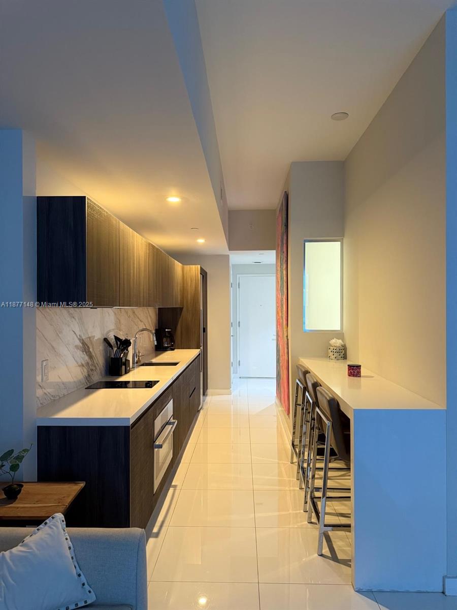 851 Northeast 1st Avenue, Unit 302 Miami, FL 33132 - Photo 25 of 30 a large kitchen with a large counter top a sink a stove and a refrigerator