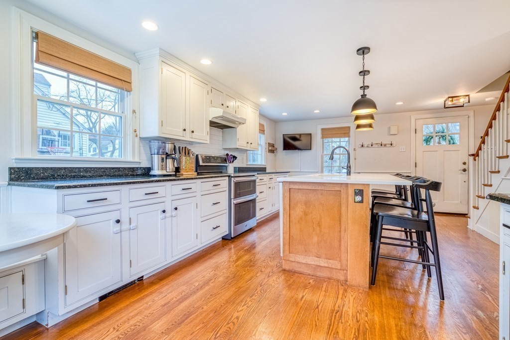 49 Jean Street Framingham, MA 01701 - Photo 5 of 41 a kitchen with stainless steel appliances kitchen island granite countertop a stove a sink dishwasher and white cabinets with wooden floor