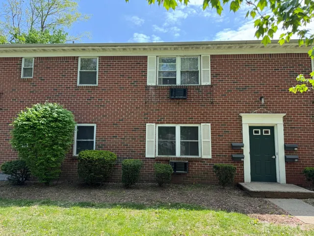 a view of a brick house with a yard and plants