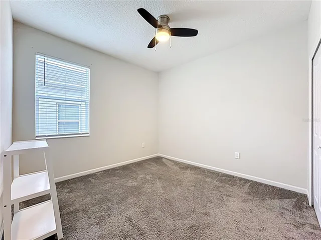 an empty room with a window and a ceiling fan