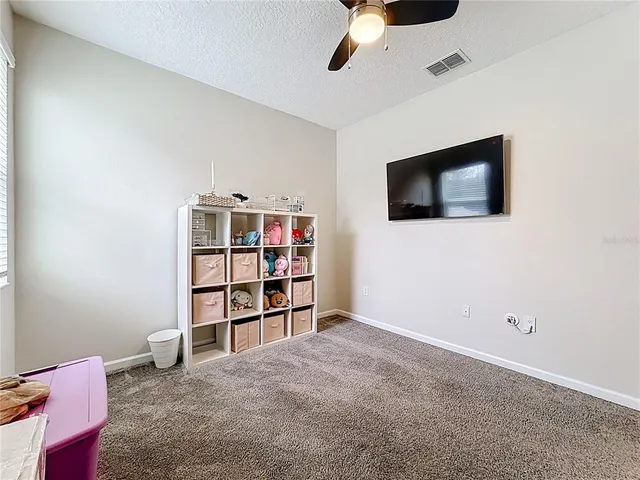 a living room with a flat screen tv and a ceiling fan