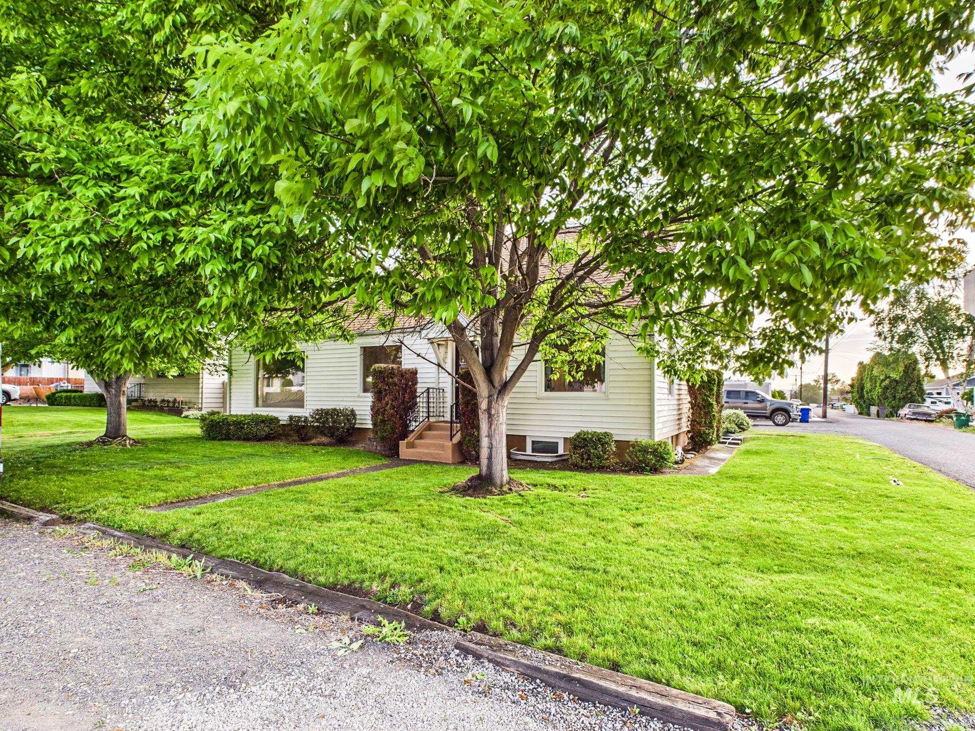 3422 6th Street Lewiston, ID 83501 - Photo 43 of 43 White siding exterior with a prominent front lawn, mature trees, and an entryway featuring steps with black railings