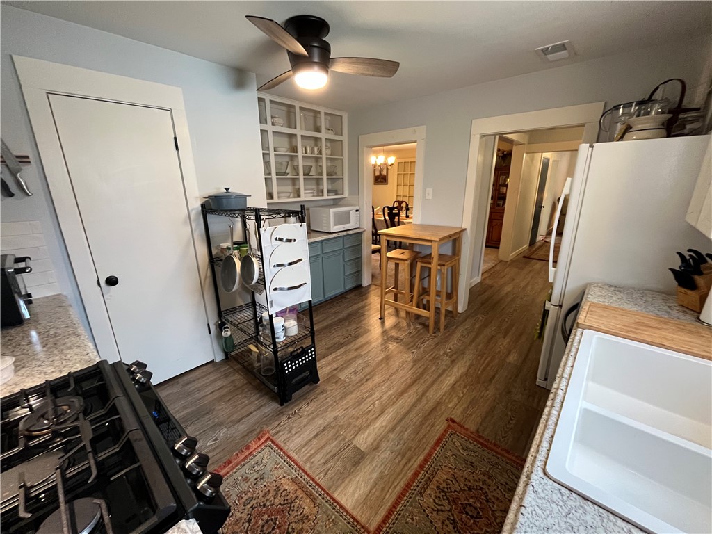 1102 North Travis Avenue Cameron, TX 76520 - Photo 23 of 48 Kitchen with white appliances, dark wood-type flooring, light countertops, ceiling fan, and glass insert cabinets